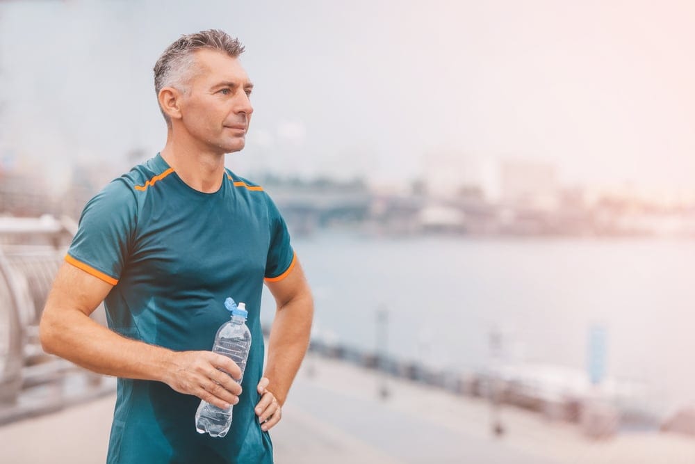 Middle aged man exercising during his fitness routine holding a water bottle