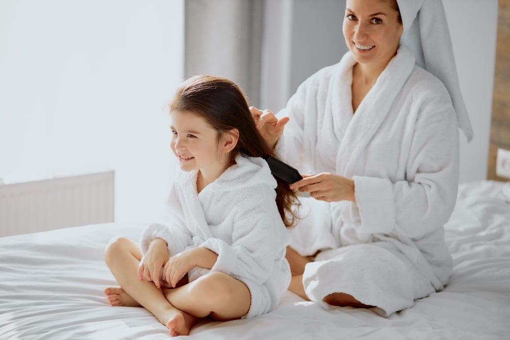 Mother brushing her daughter's hair.