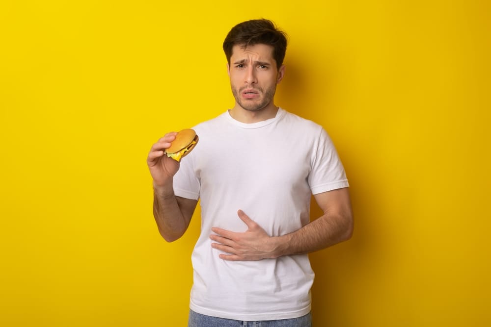 Man eating unhealthy and regretting it.