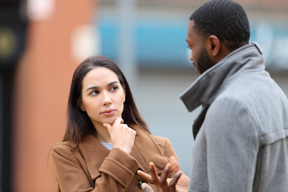 Two coworkers discussing work on the street.