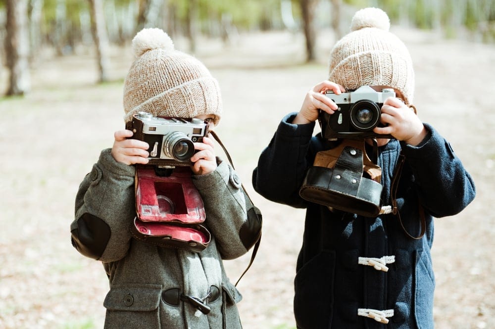 Two boys taking photos with a camera.