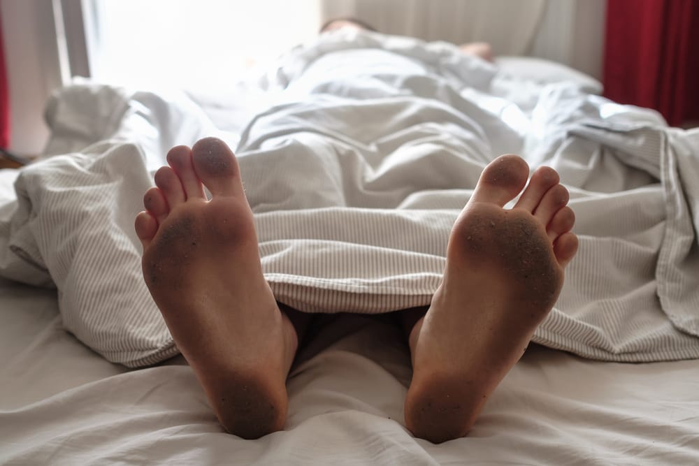 Dirty bare feet in bed.