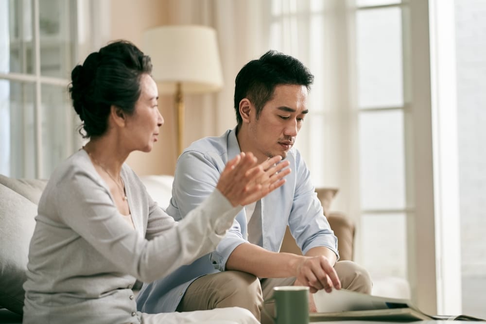 Senior,Asian,Mother,And,Adult,Son,Sitting,On,Couch,In