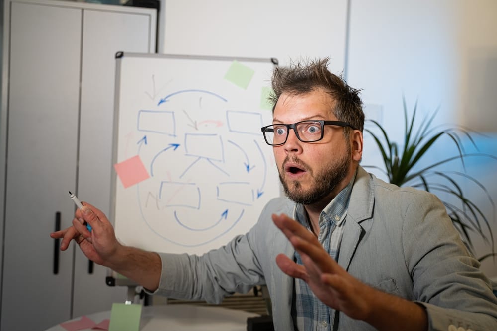 Man in front of a dry board trying to explain a conspiracy.