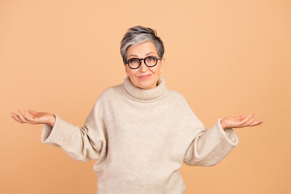 A senior woman shrugging her shoulders to say she is clueless