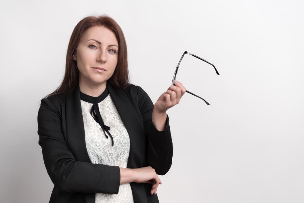 Confident woman holding her glasses.