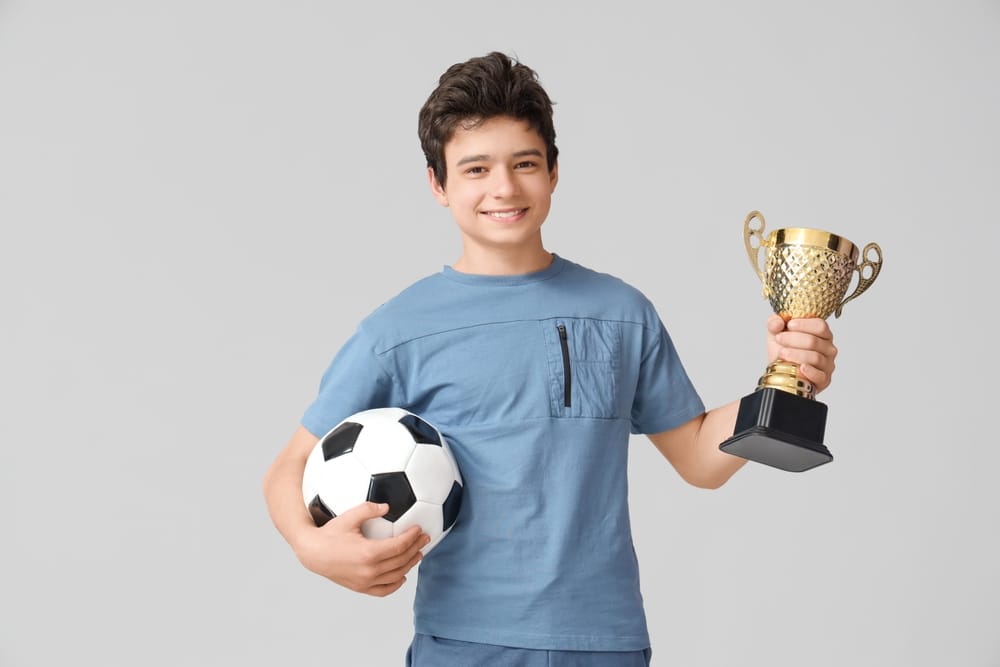 Teenage boy with soccer ball and trophy.