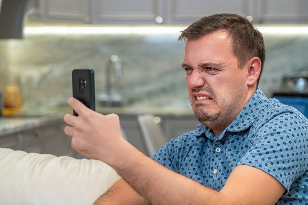 Man looking at his dirty phone.