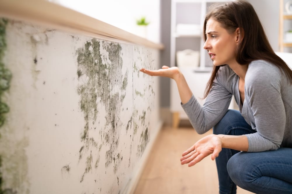 Woman looking at dirt on her baseboards.