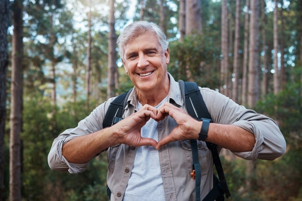 Older man walking in woods.