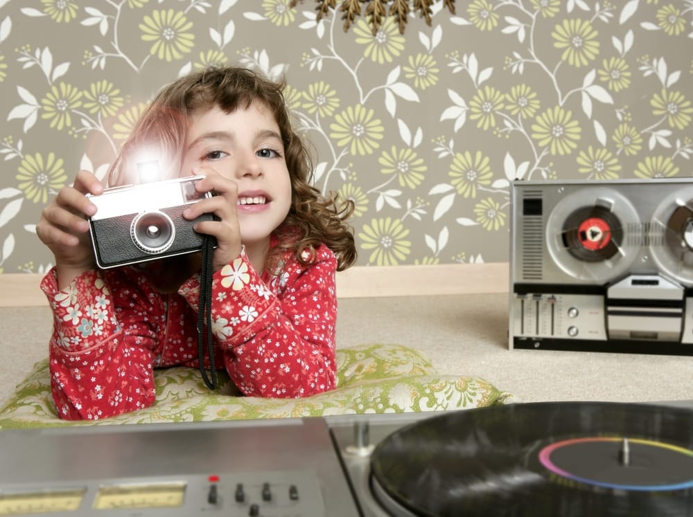 Little girl in front of floral wallpaper.