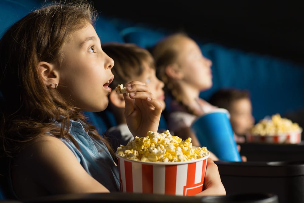 Children eating popcorn at the theater.