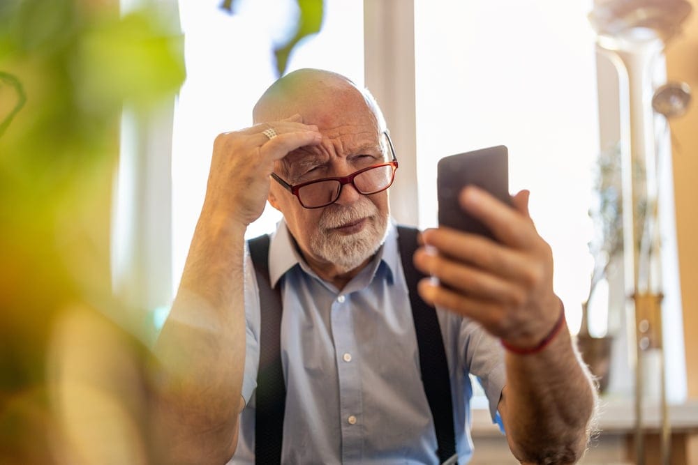 Senior man staring at his phone.