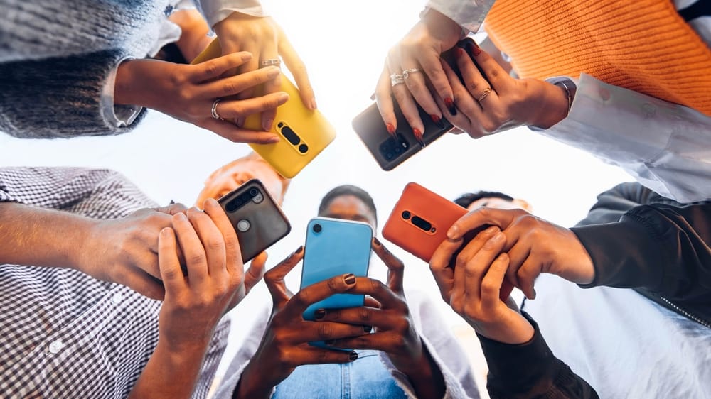 Teens in a circle holding their phones.