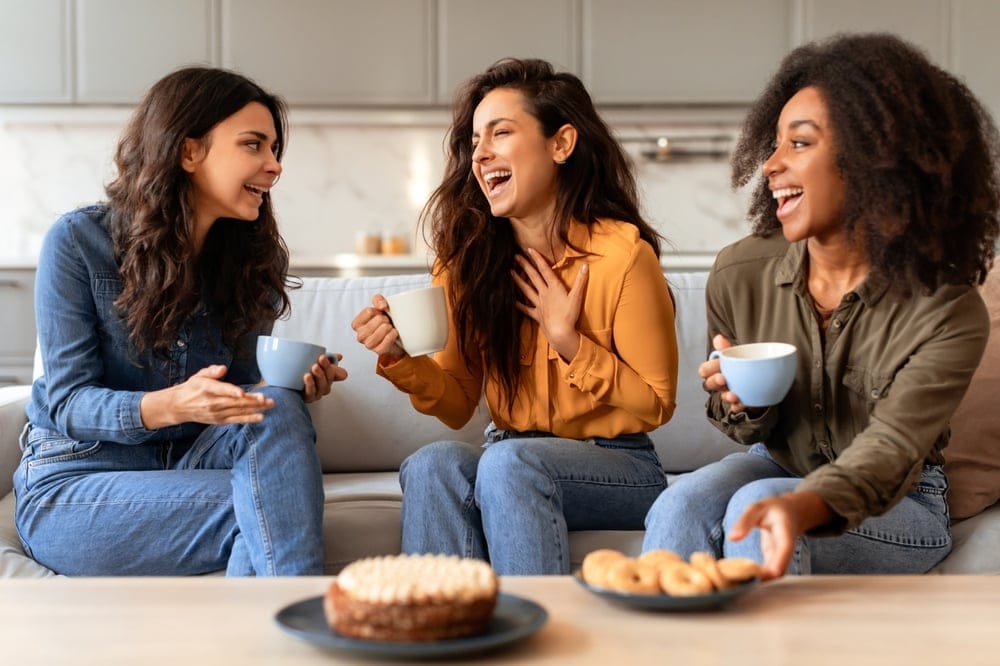 Three female friends share a moment over coffee.