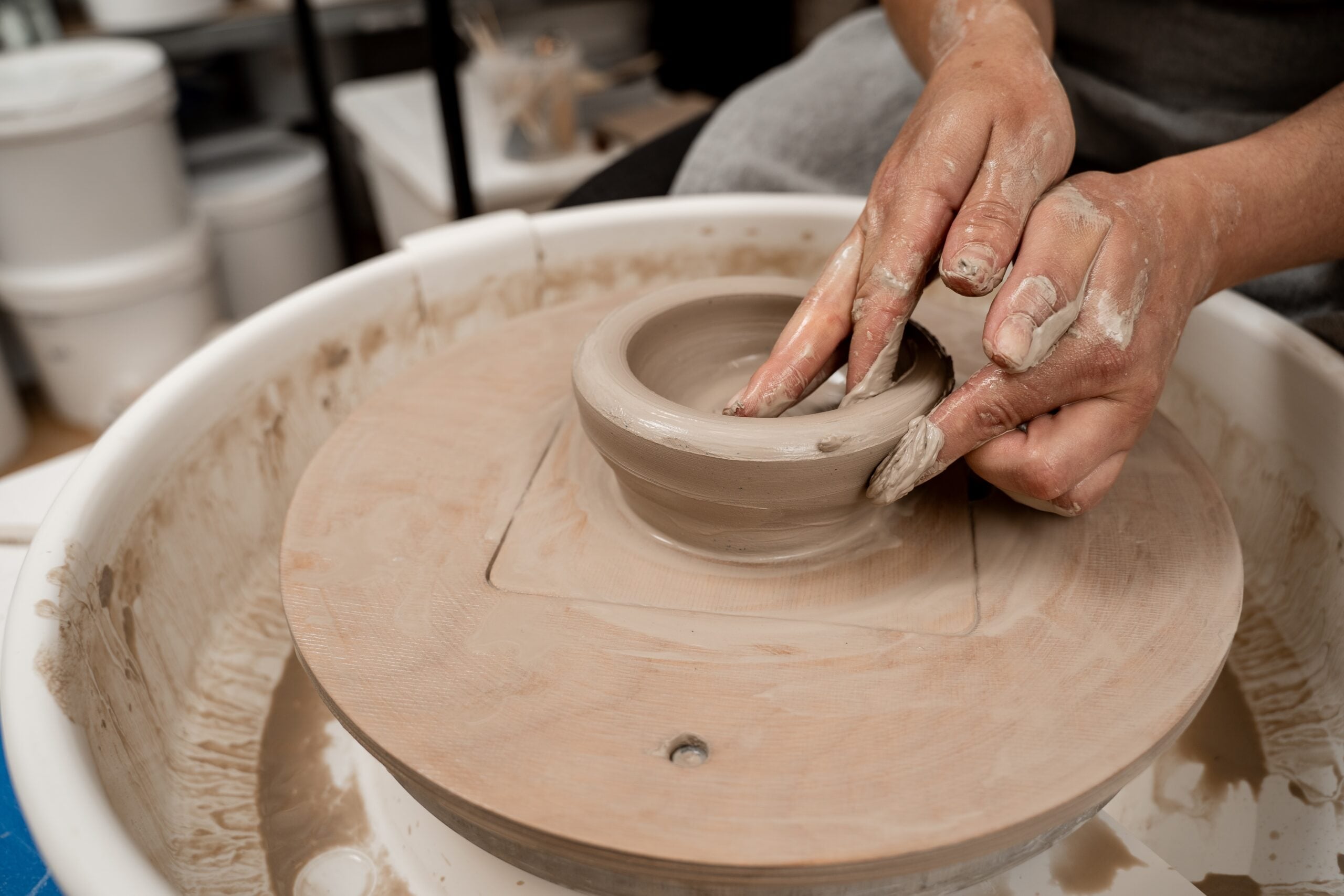 Learning how to model clay on a wheel.