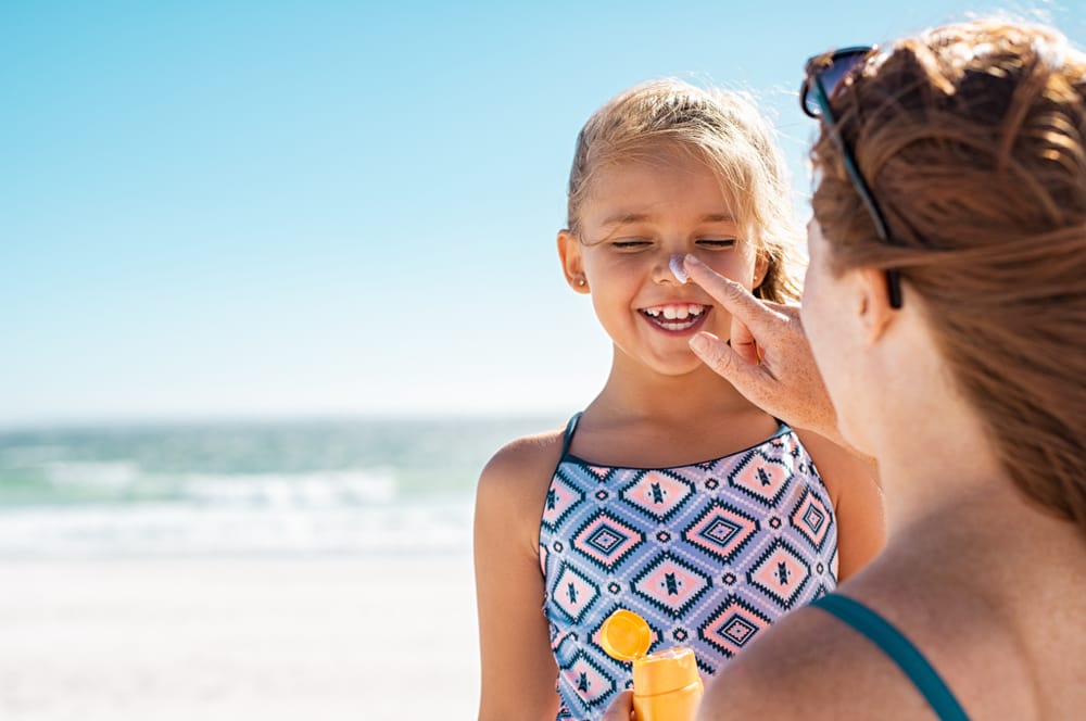 Mother applying sunscreen to her child's face.