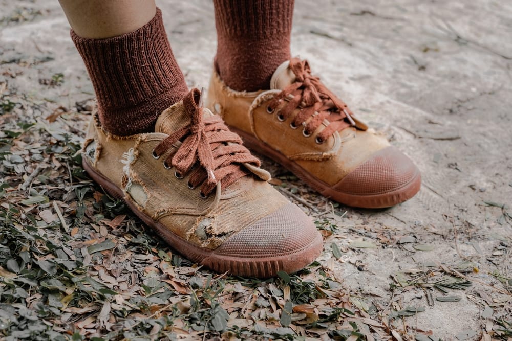 Young child wearing torn shoes.