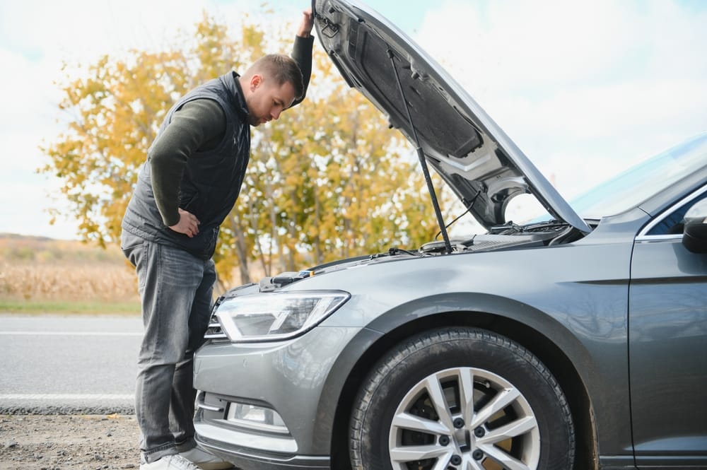 Man looking in the hood of car.