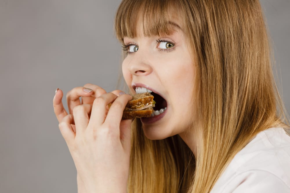 Young woman eating a sandwich.