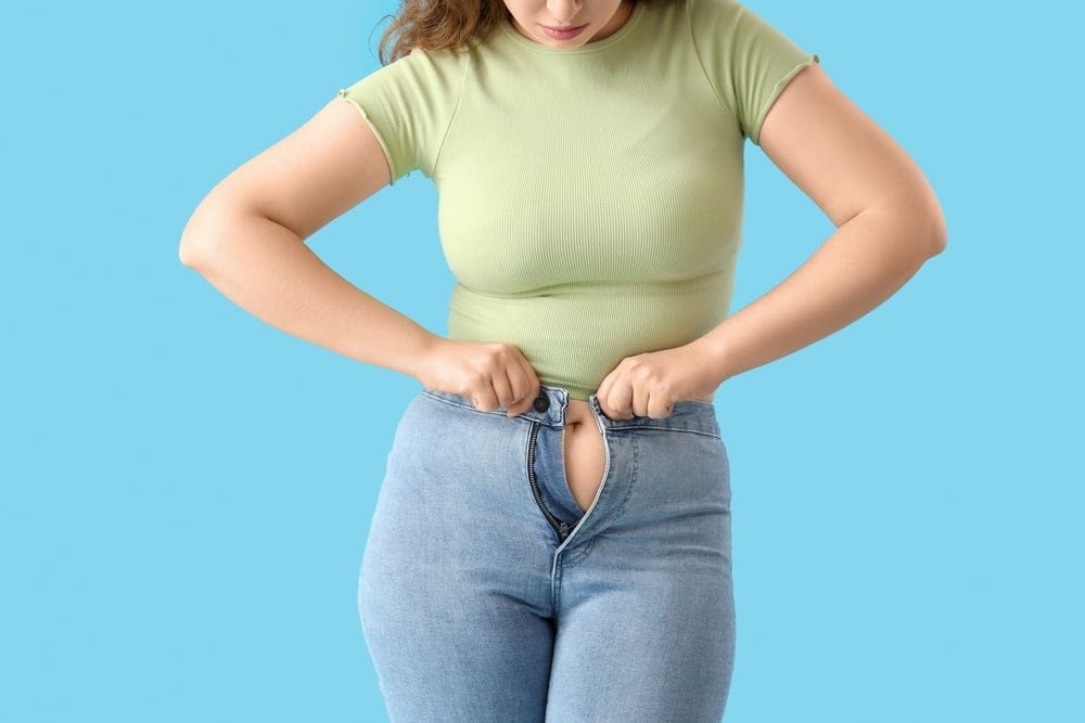 Woman trying to zip up her jeans.