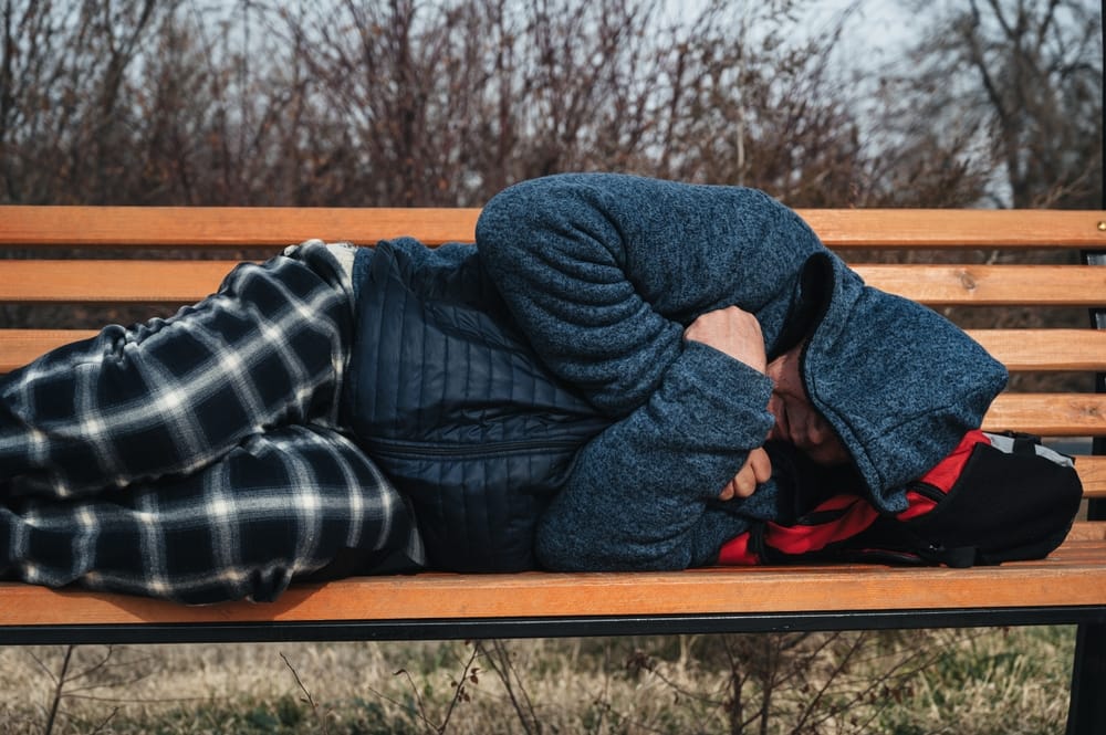 Homeless person on a street bench.