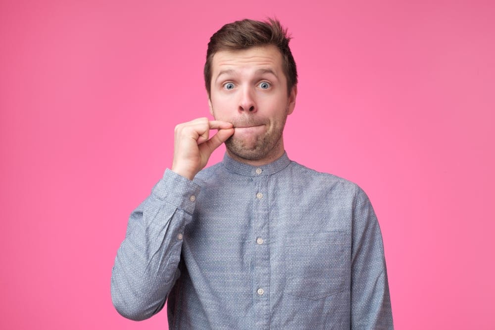 Young man zipping his lips.