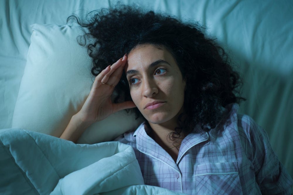 Woman laying in bed unable to sleep.