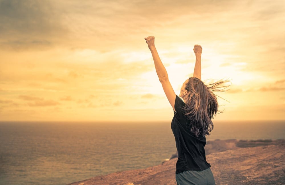 Woman with her hands in the air on the beach.