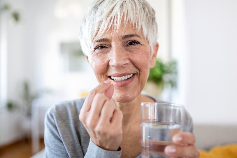 Older woman smiling and drinking water.