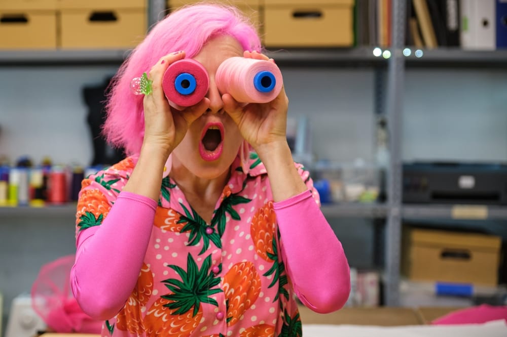 Woman with pink hair looking through binoculars.
