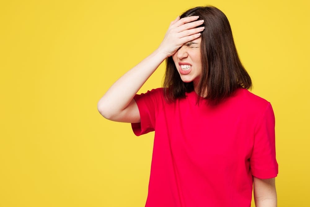Woman with her hand on her forehead looking stressed.
