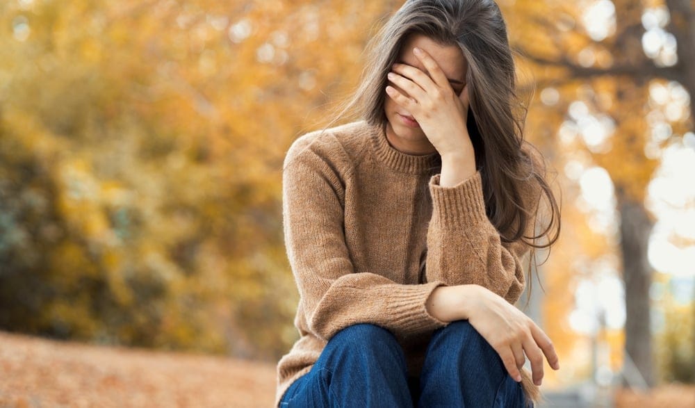Woman upset and holding her face in her hands.