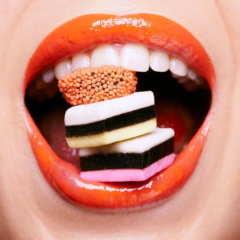 Woman's mouth eating candy.