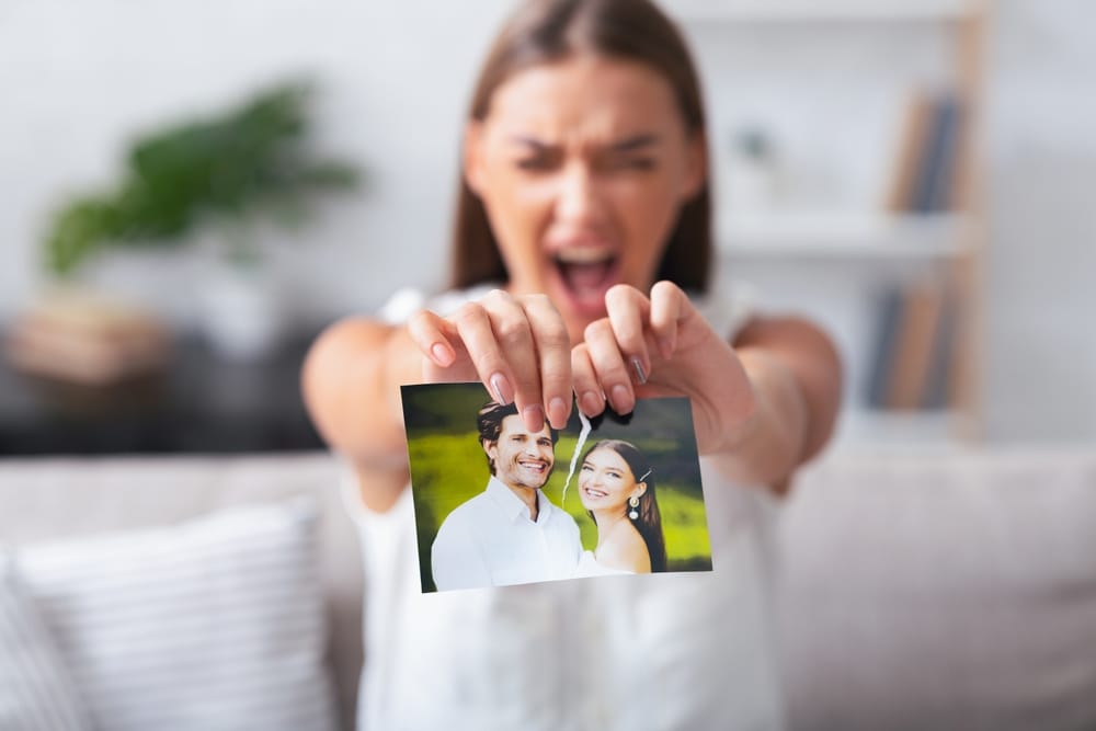 Woman tearing a photo apart of her and her partner.