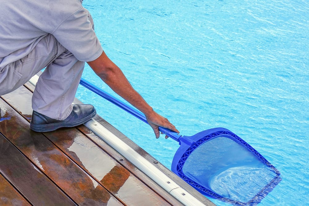 Cleaning out the pool with a net.