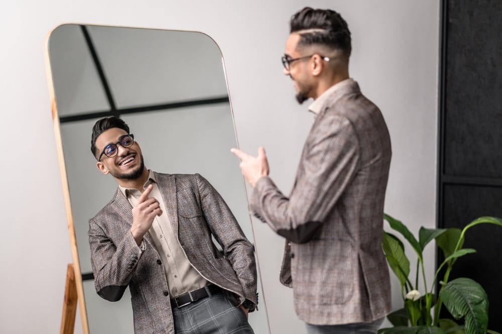 Handsome man wearing a blazer looking in the mirror.