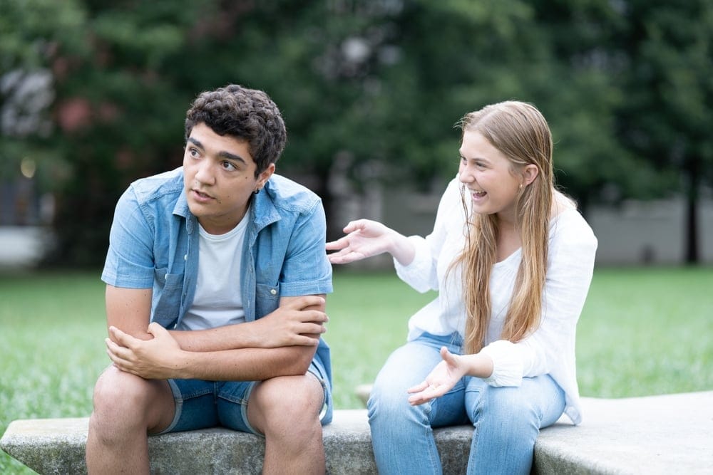 A young guy tired of listening to talkative girl at the park