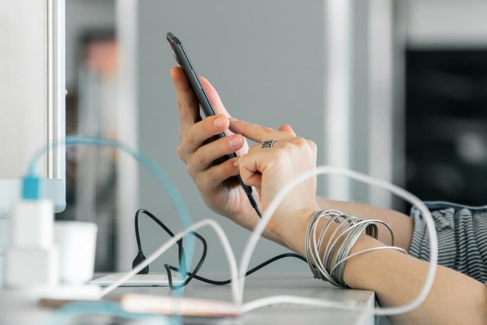A woman holding up and using her smartphone while charging