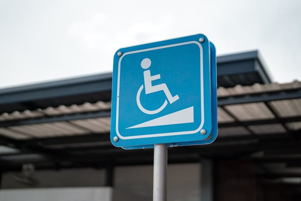 A blue wheelchair symbol on parking lot sign