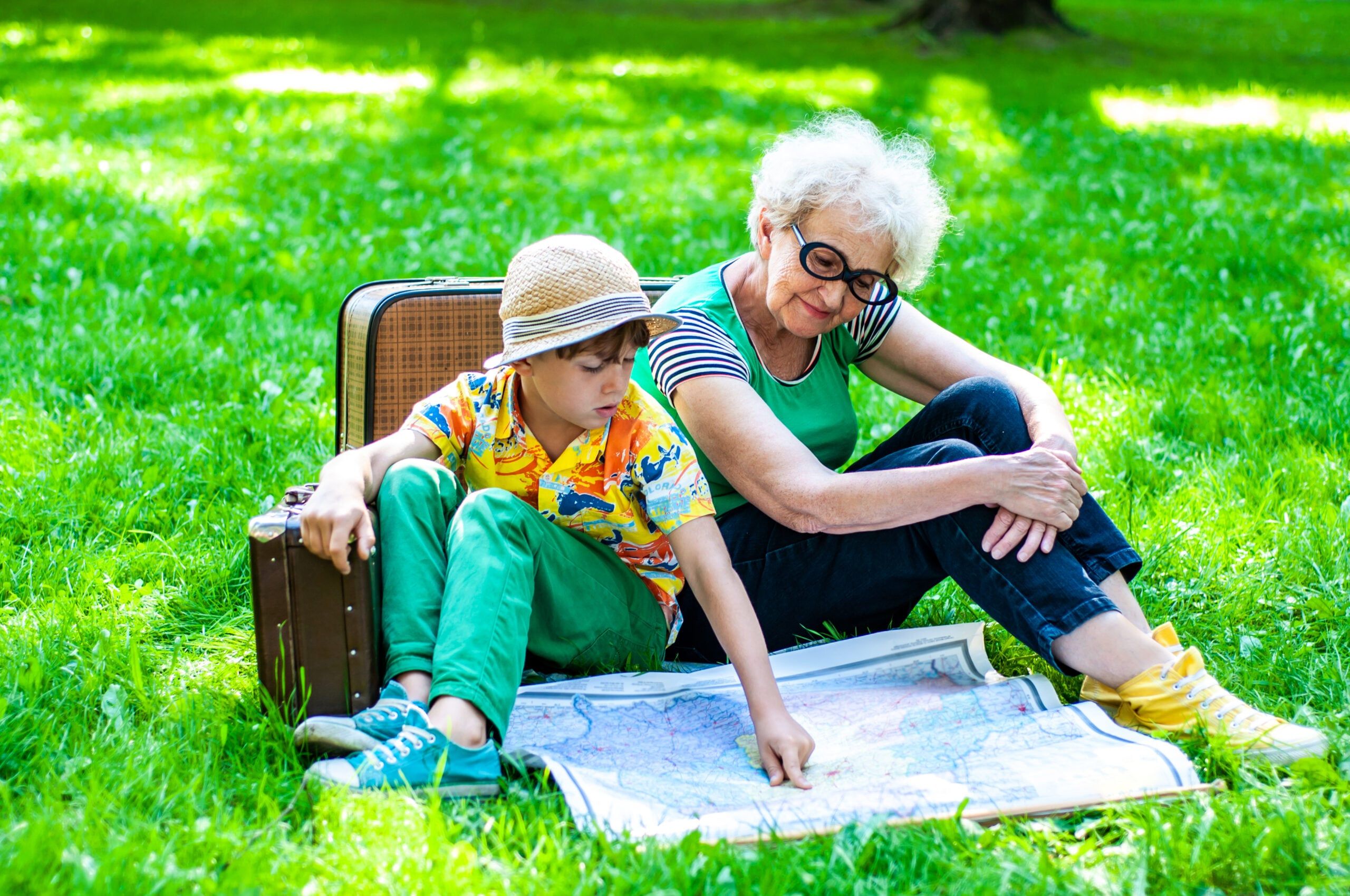 A grandmother sitting in the park with her grandson as they look at a map together.