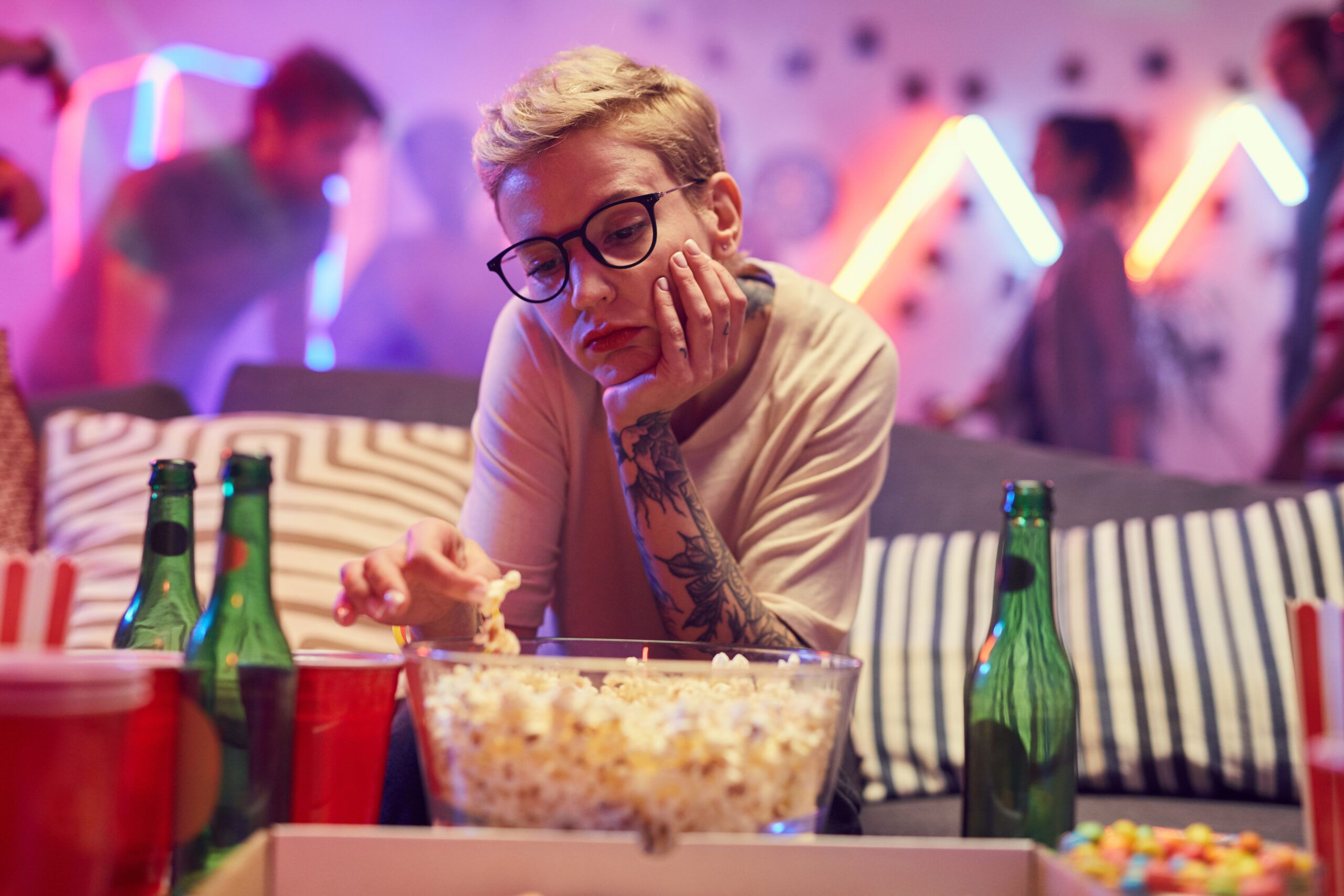 A young woman sitting alone while bored at a party.