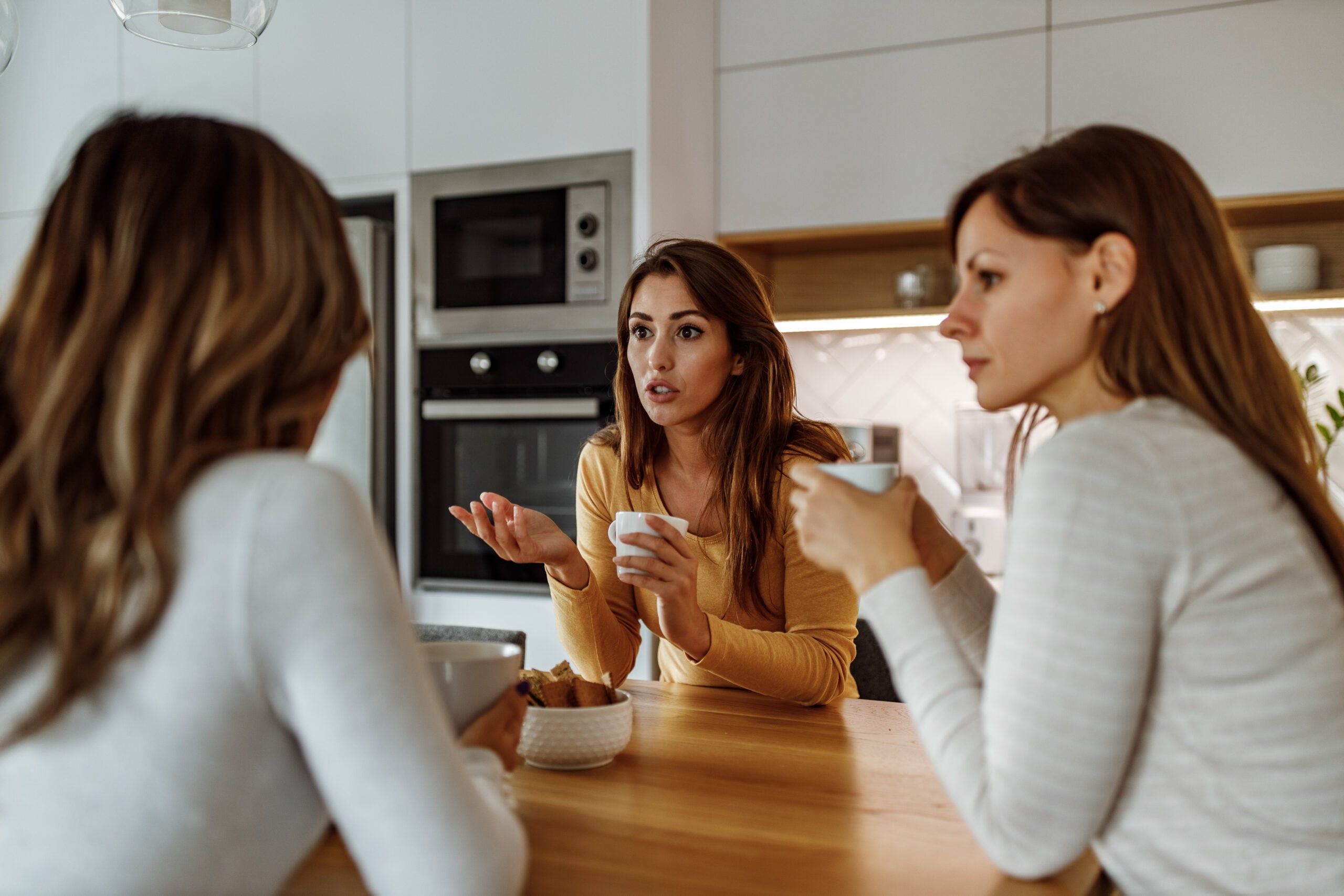 Female friends sitting together talking and drinking coffee.