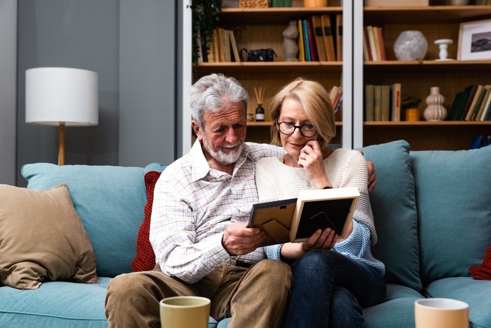 A senior couple on the couch looking at photographs together.