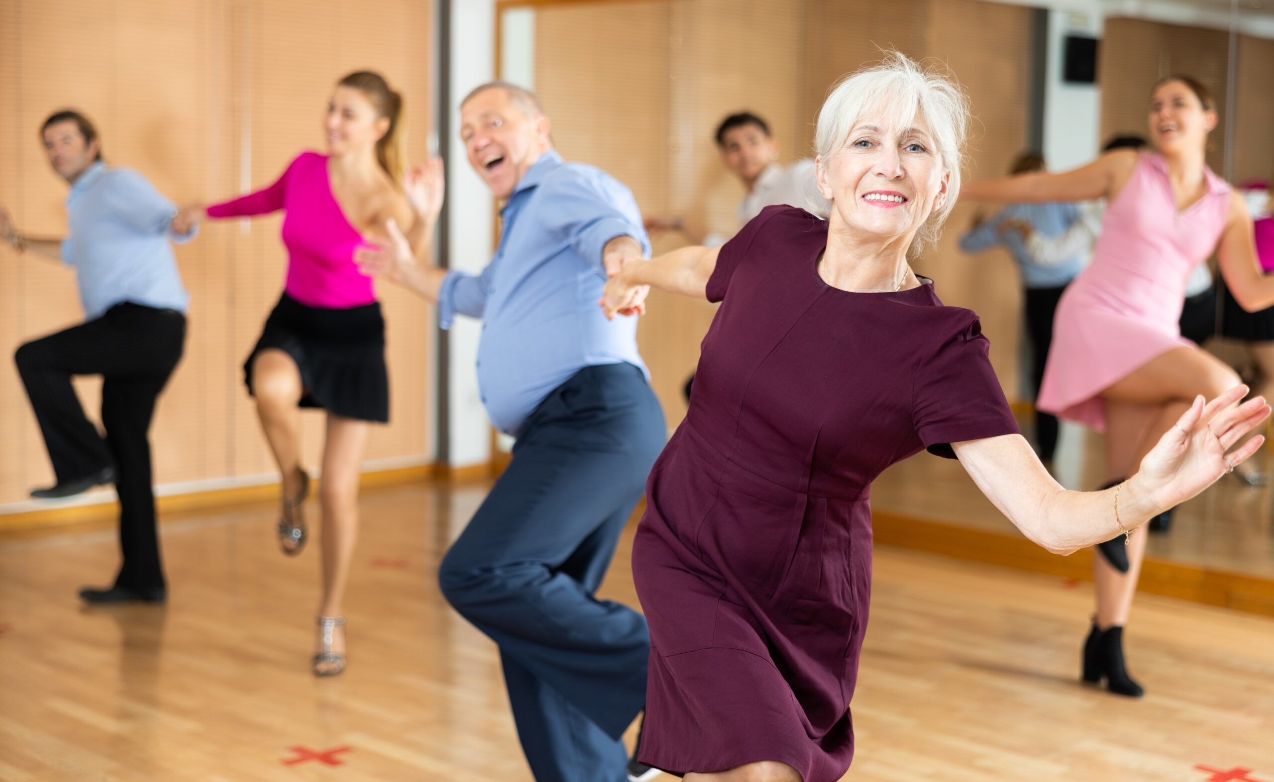A joyful group of mature men and women enjoying a dance class.