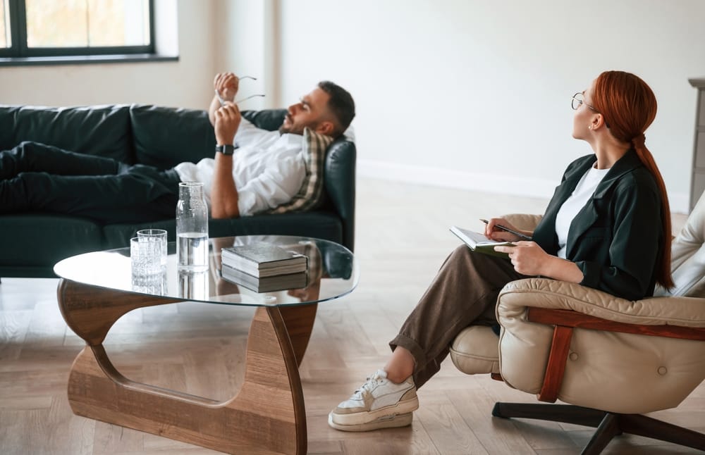 A man in therapy, talking to his therapist while lying on the couch