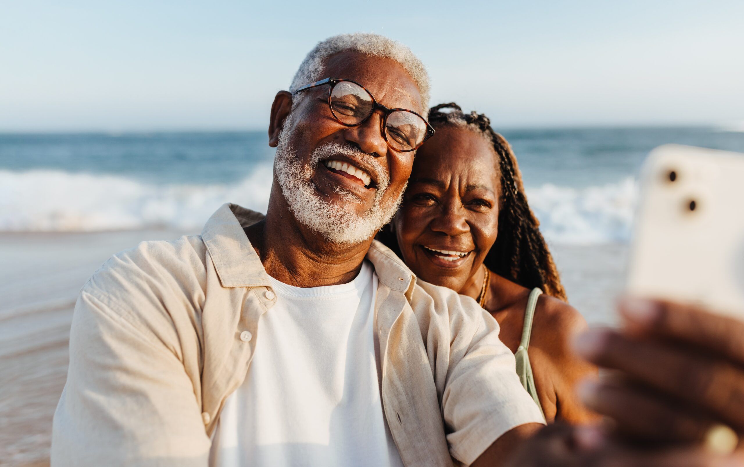 A smiling mature couple taking a selfie on the beach.