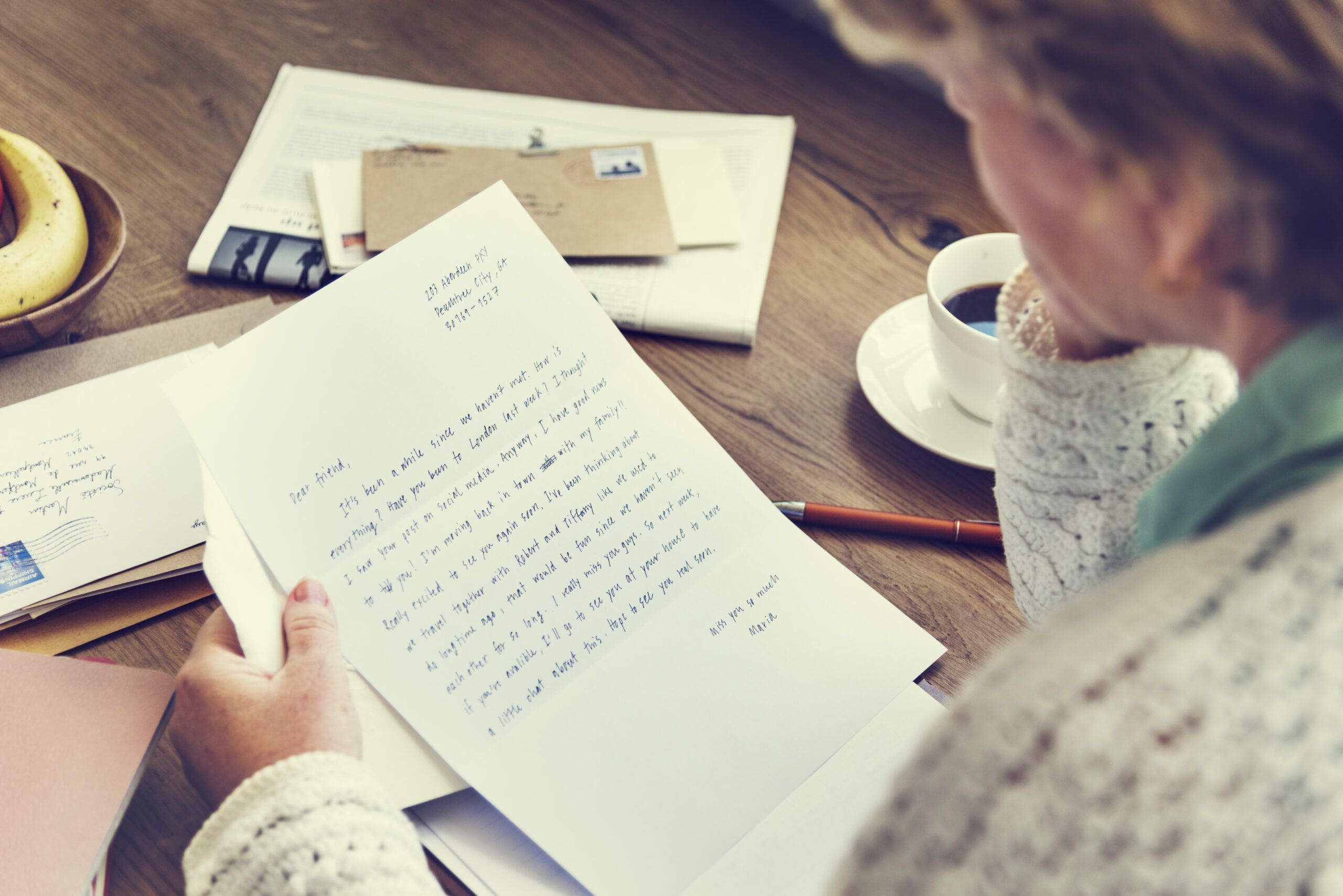 A mature woman reading a hand written letter that arrived via the mail.