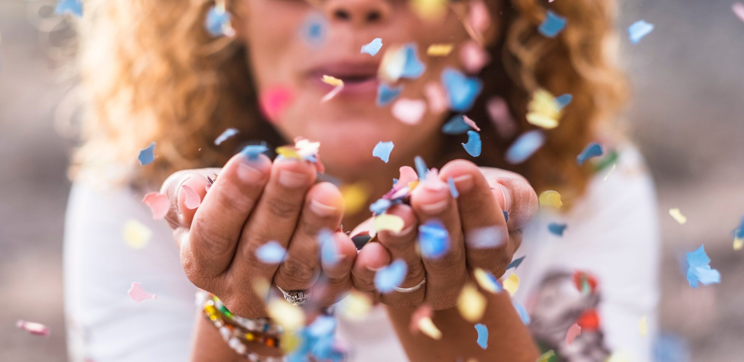 A woman blowing confetti from her hands in celebration.