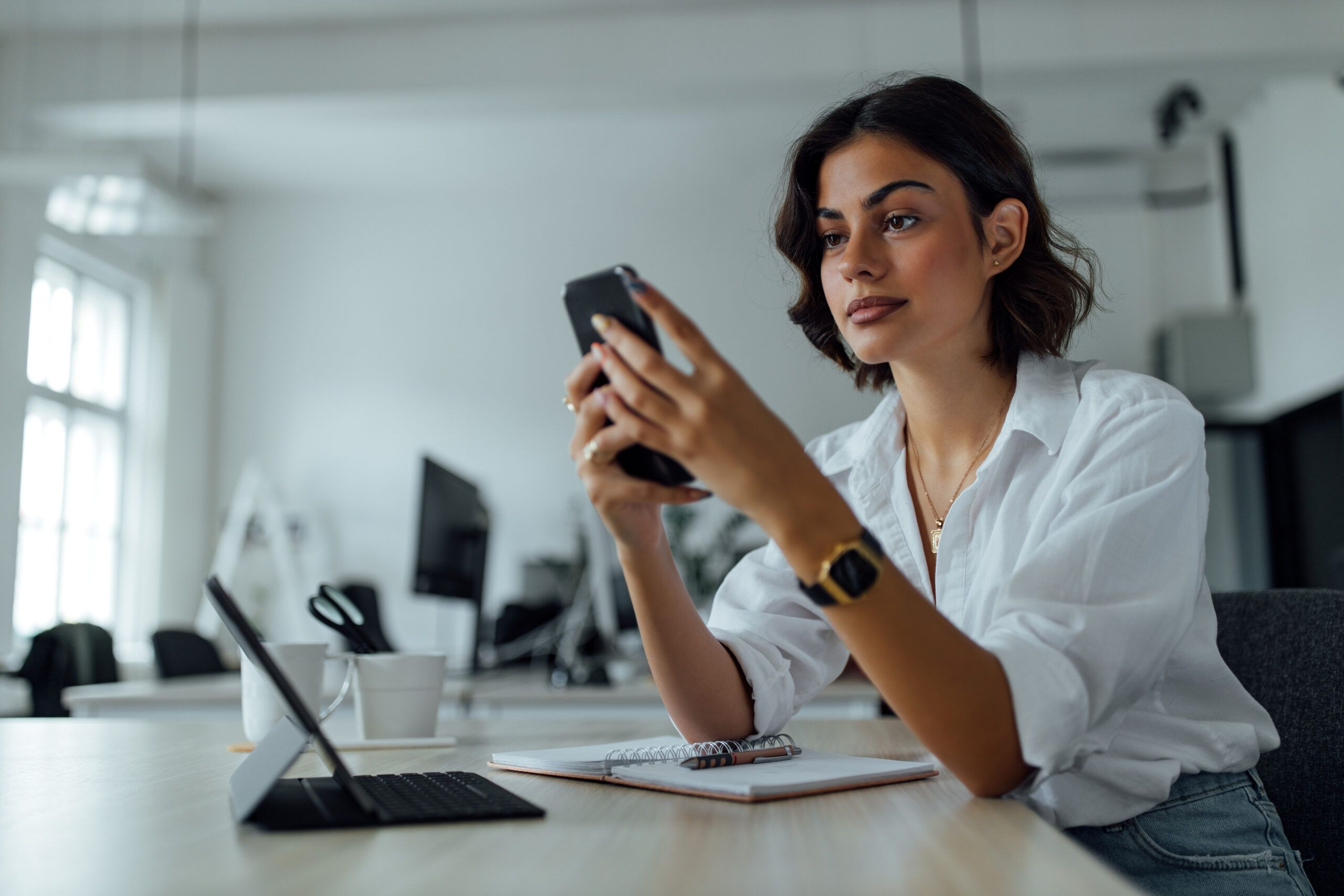 Woman in her office looking at her cell phone.